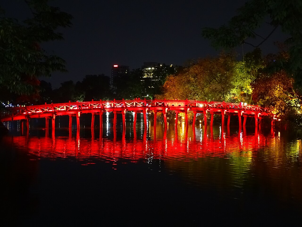 The red The Huc Bridge illuminated at night over Hoan Kiem Lake